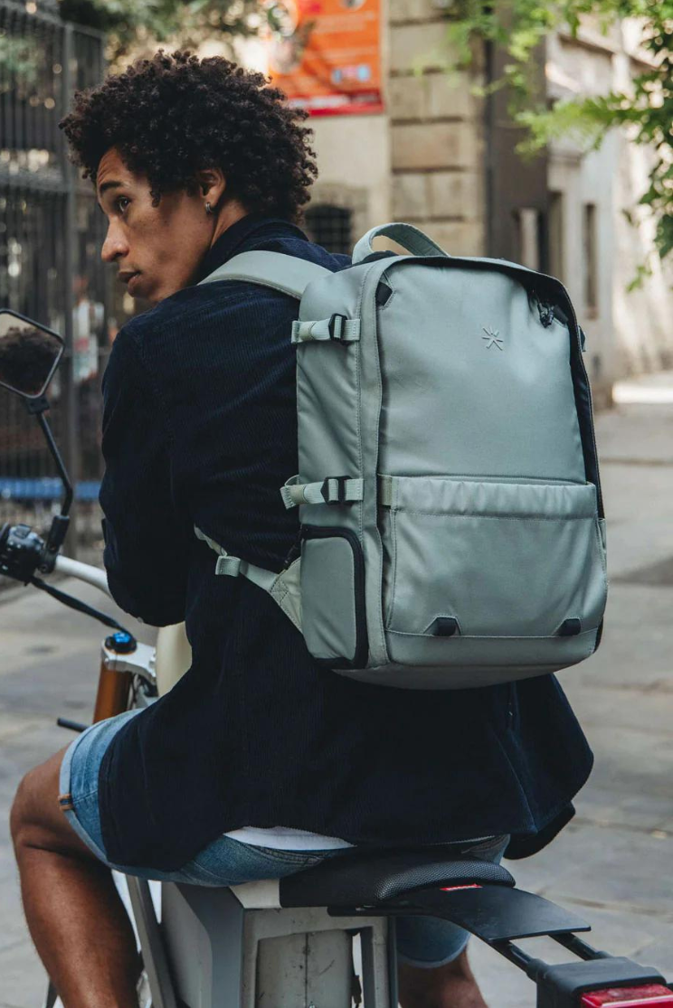a person on a bike models a pale blue hive backpack from tropic feel