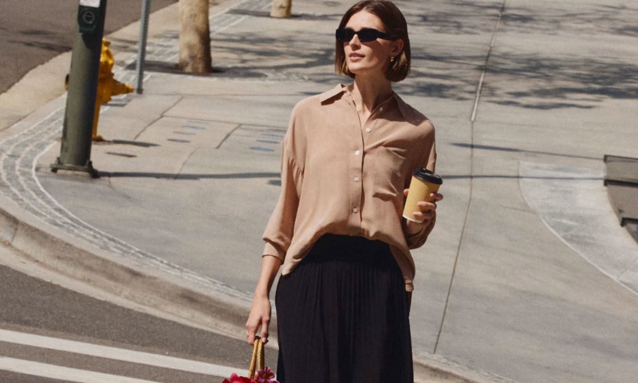 Woman wearing shades and linen button up shirt in brown and black skirt in the street