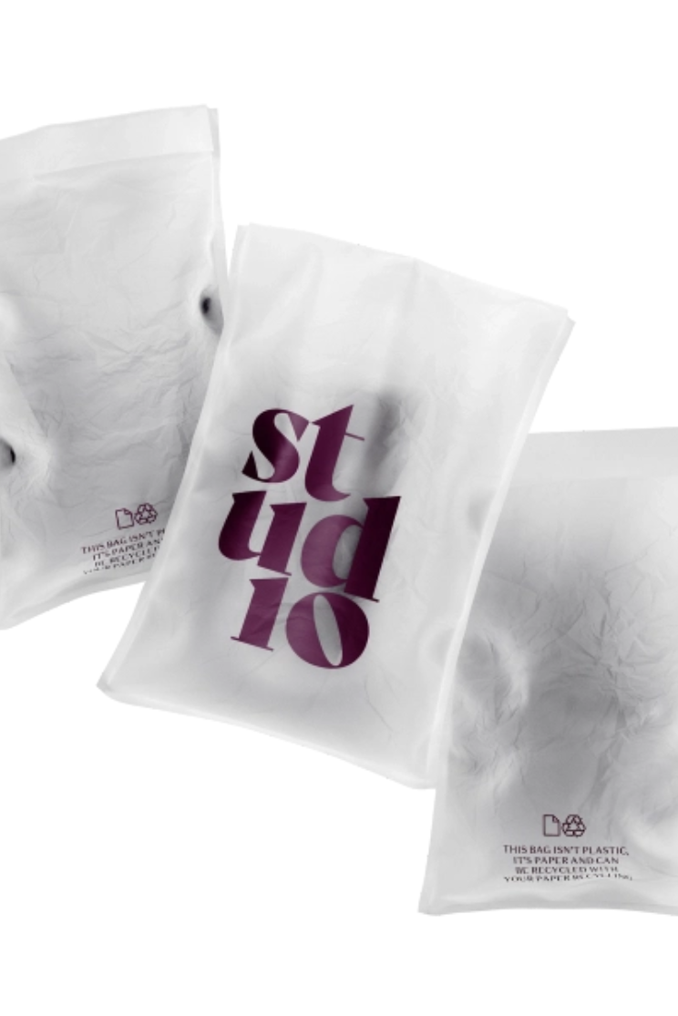 a paper polybag with purple writing reading "studio" and "this bag isn't plastic, it's paper and can be recycled"