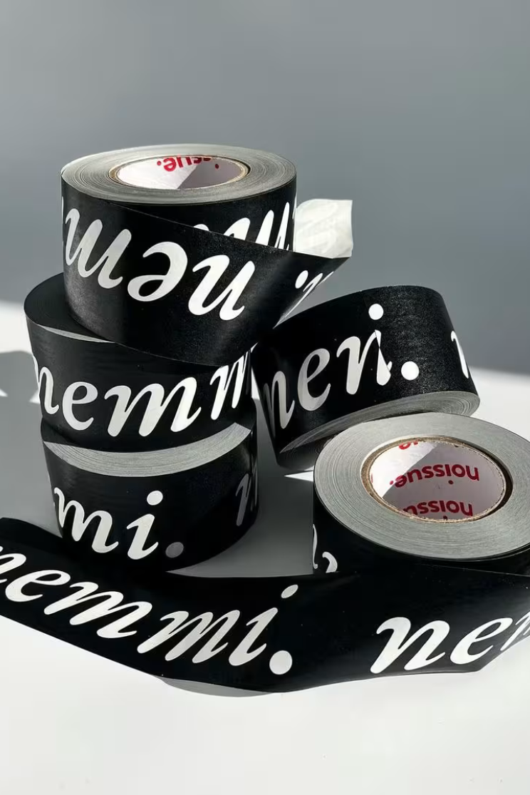 a pile of tape roles unfurled at different lengths. they are all black with white lettering reading 'nemmi'