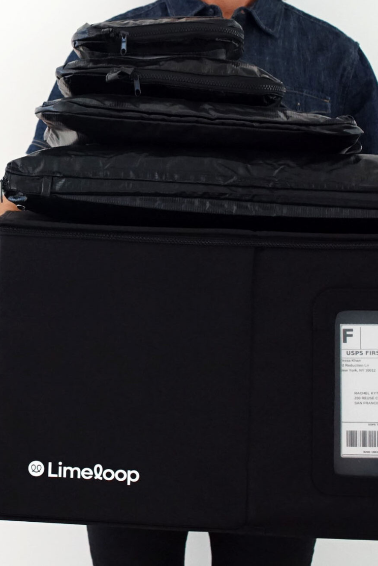 a person holds a large black limeloop box stacked with reusable mailers