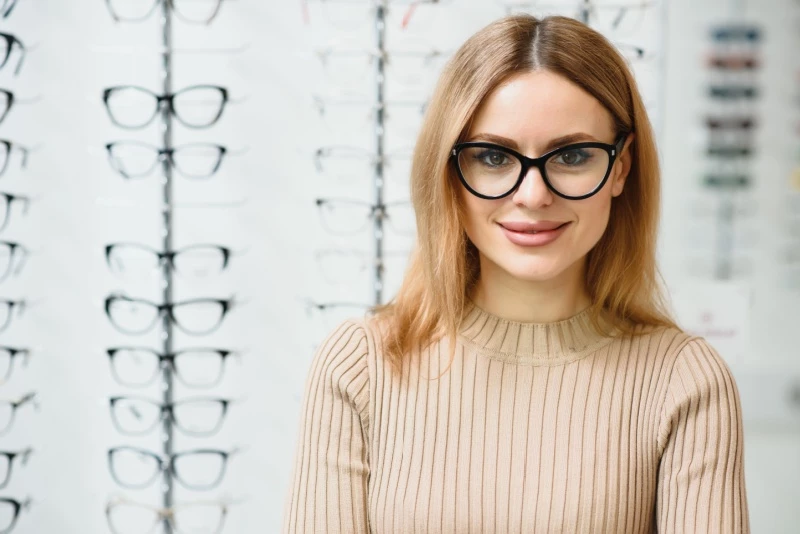 young woman trying on glasses at optimists,