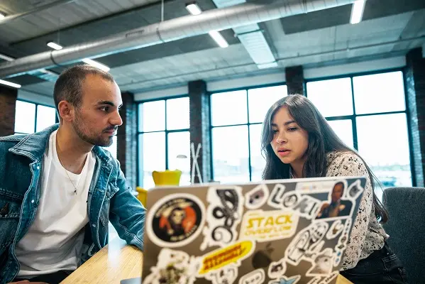 Two colleagues working together and collaborating in front of a computer.