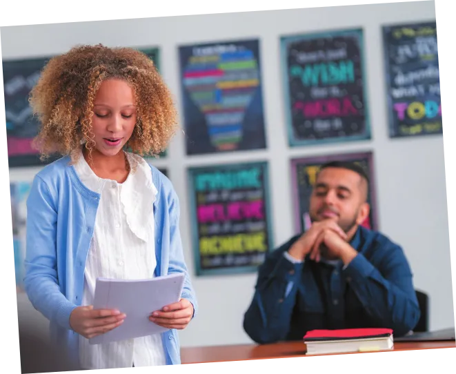 Imagem de uma menina em pé, lendo uma folha de papel. Ela está perto de um homem sentado diante de uma mesa.