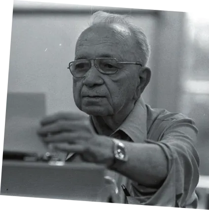 Imagem de Mário Quintana utilizando máquina de escrever. Ele é idoso, calvo e usa óculos.