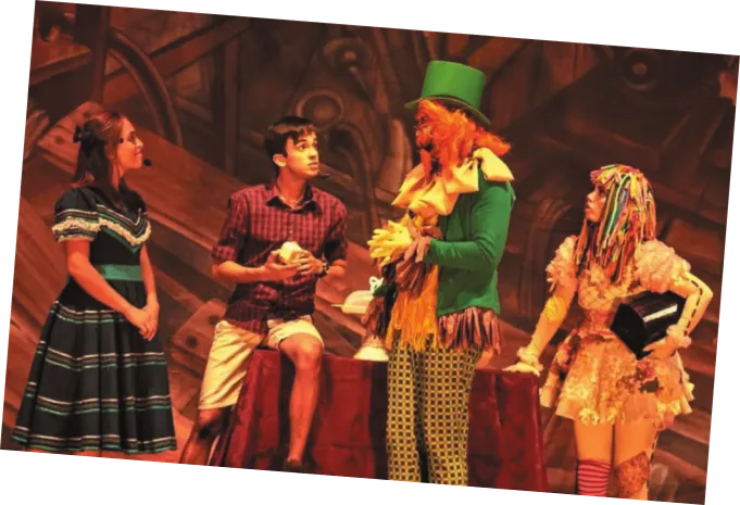 Imagem de cena de uma peça de teatro. Os atores interpretam os personagens Narizinho, Pedrinho, Visconde de Sabugosa e Emília.