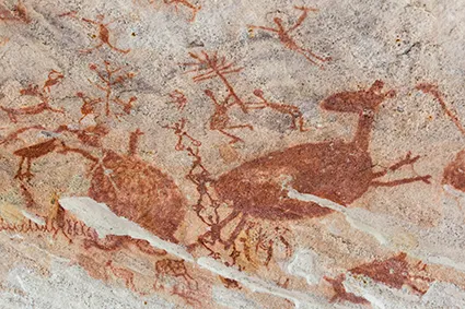 Imagem de pintura rupestre na parede interna de uma caverna representando animais e objetos.