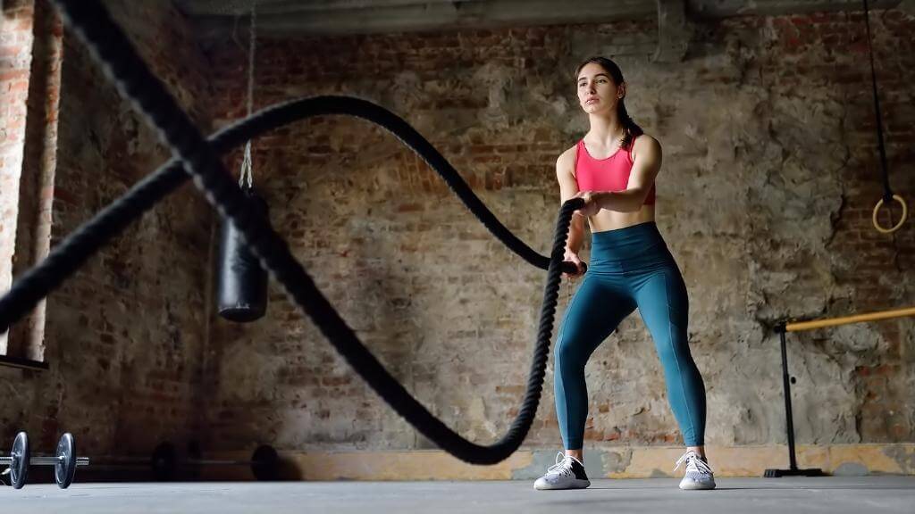 Young woman working out with ropes at the gym