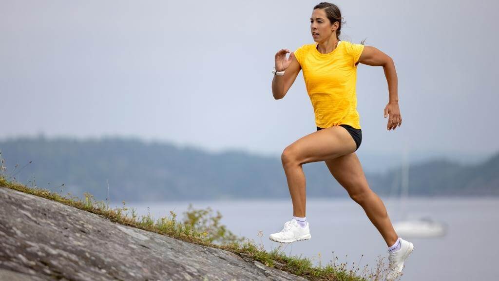 Young woman running up a hill