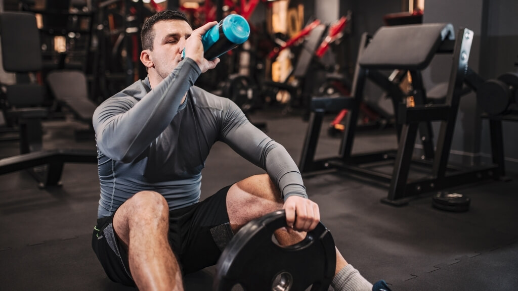 Young muscular man taking a break from his workout to stay hydrated