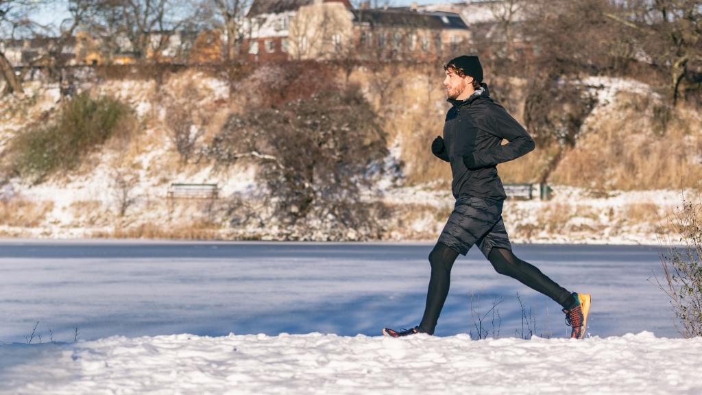 Runner in winter athletic clothing, jogging in snow