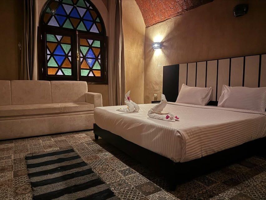A bedroom, with stained glass and a vaulted brick ceiling
