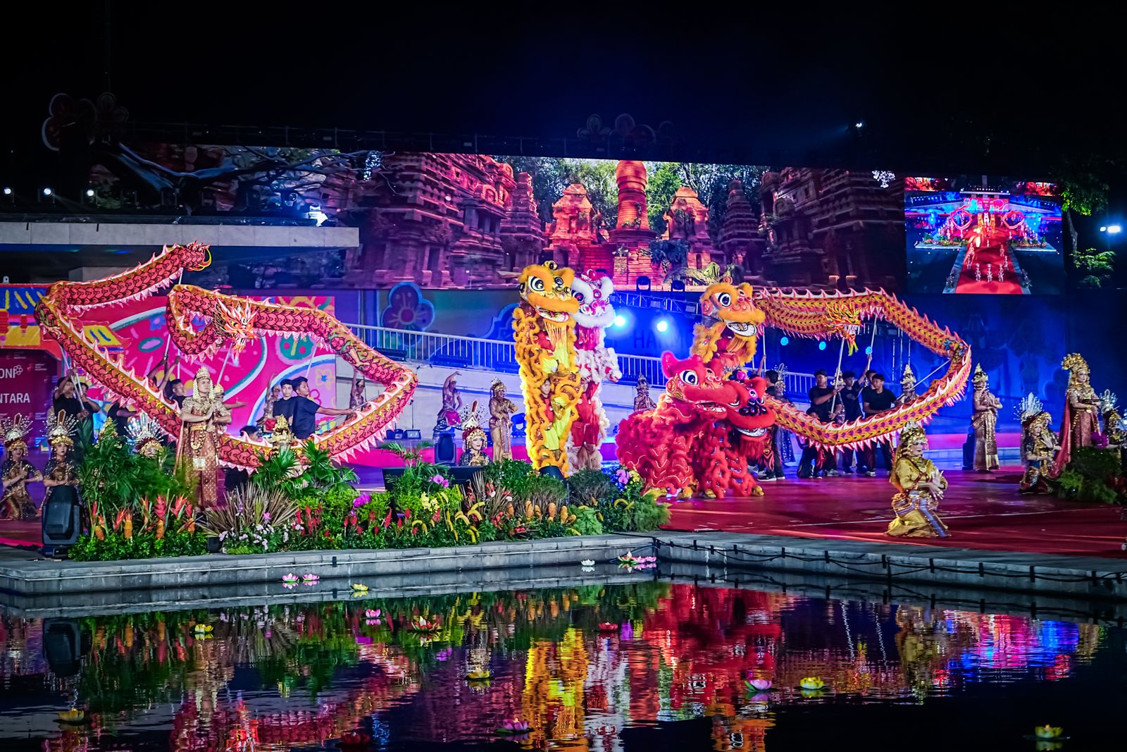 A vibrant cultural performance featuring dragon dancers and traditional costumes, set against a colorful backdrop and reflecting in water.