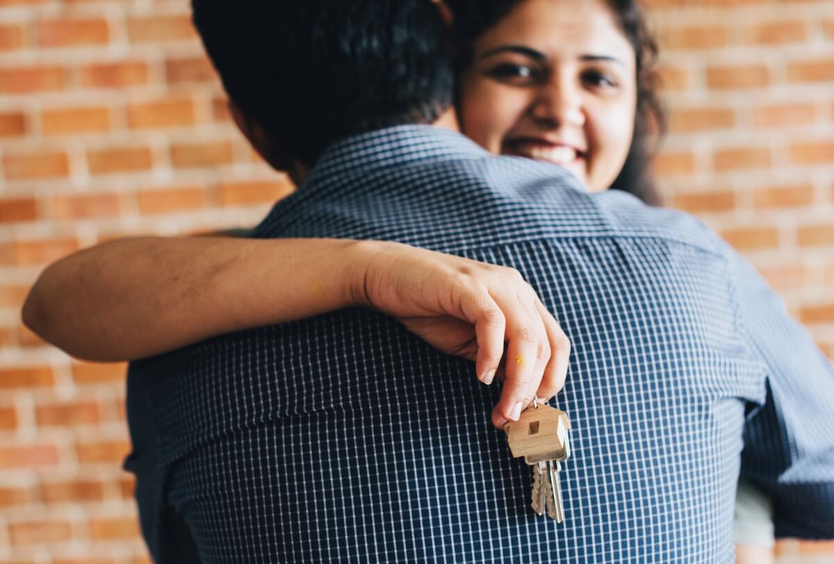 Couple hugging and holding keys to new home