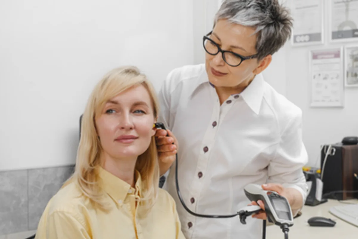 audiologist fitting a hearing aid on a patient
