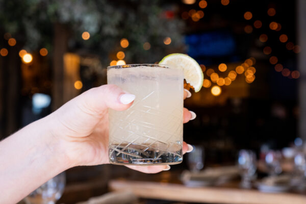 El Segundo Sol Margarita being held up in front of the El Segundo tables and patio.
