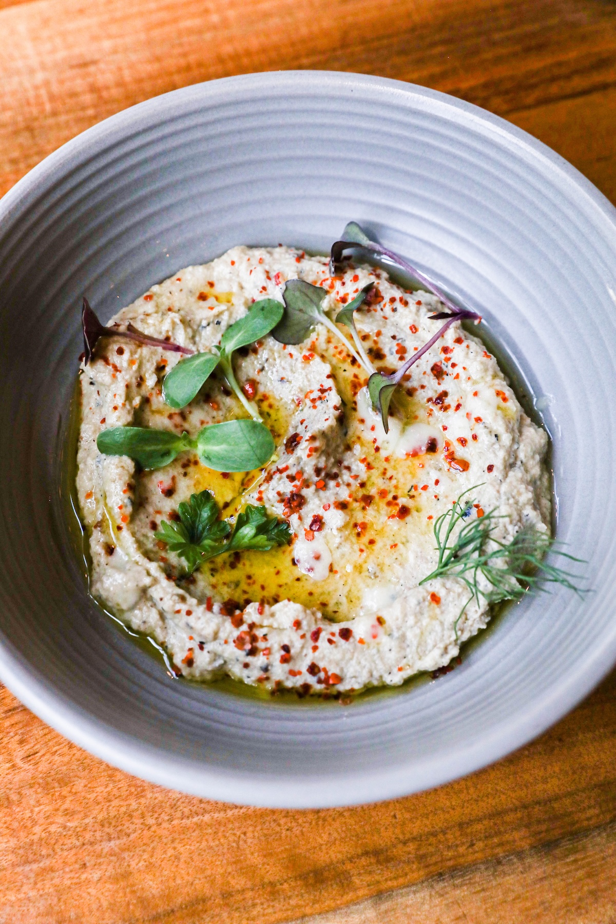 charred eggplant spread in a bowl with green garnish on top