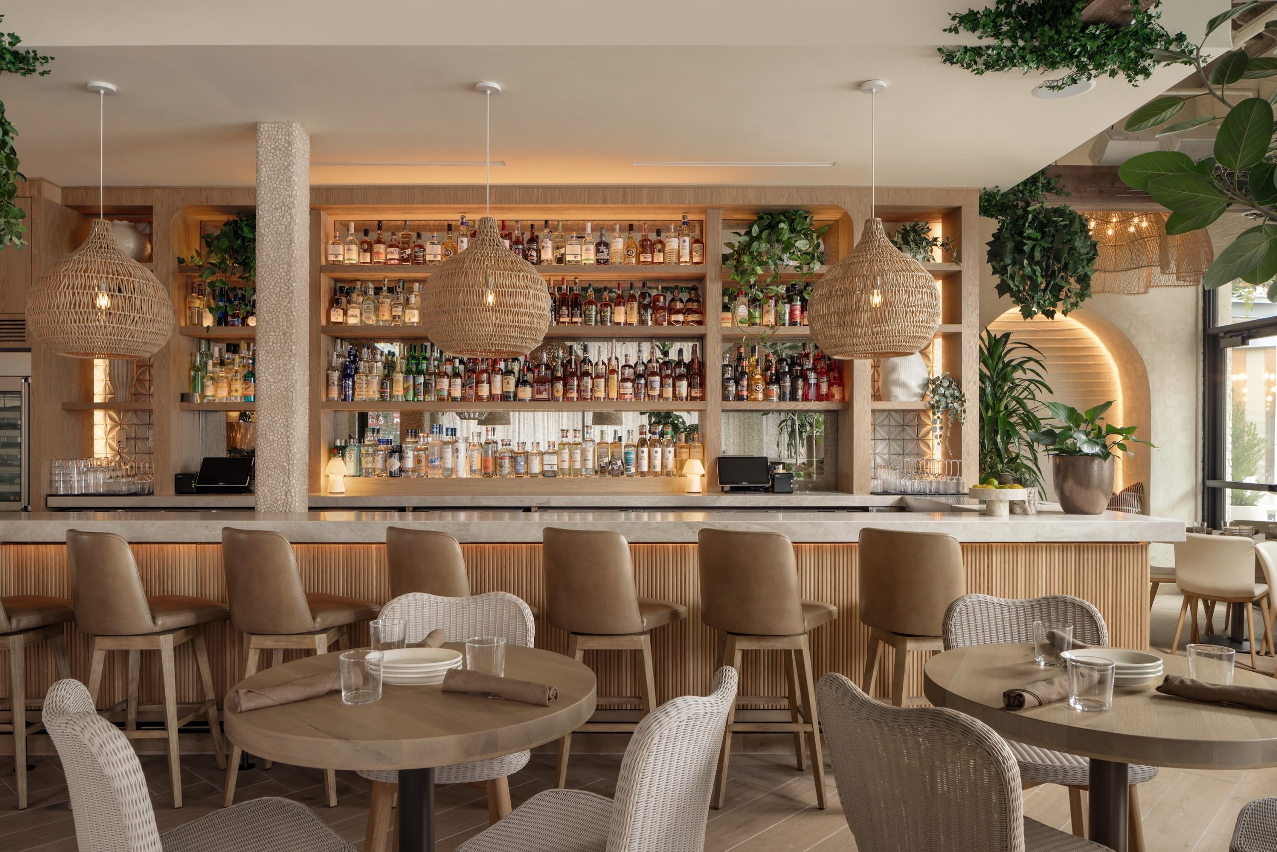 interior photo at Ema of a bar and there is bottles and greenery