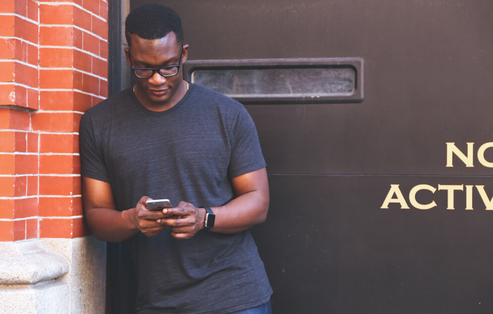 Person reading Emet on a phone beside a brick wall