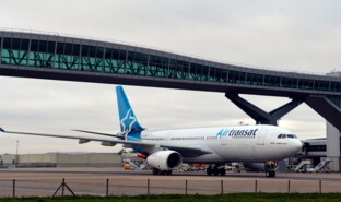 Airlines - Airtransat aircradft passing under Pier 6 Bridge at London Gatwick Airport.jpg