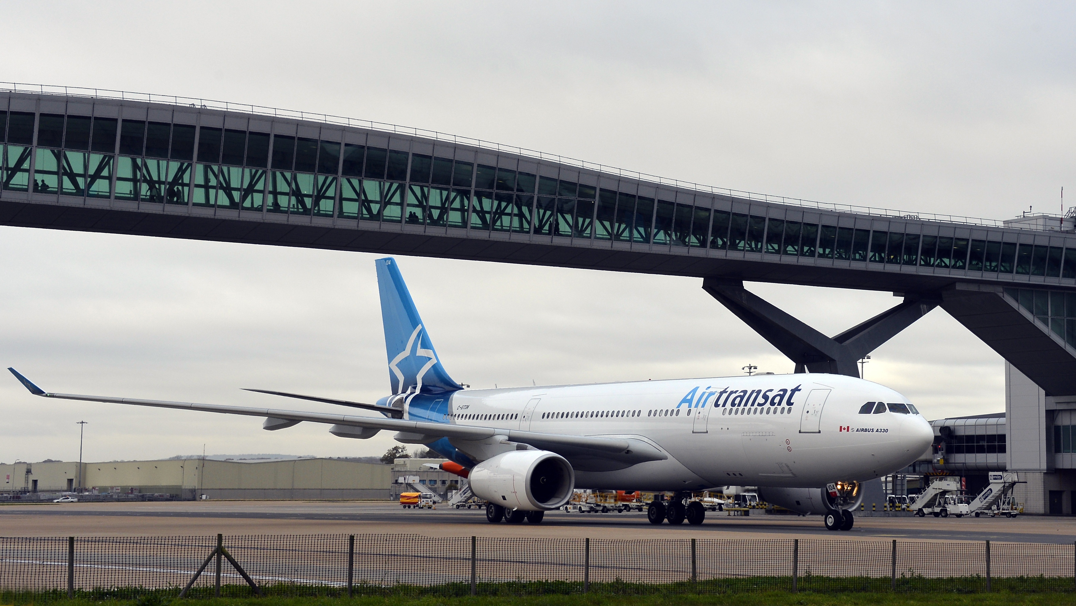Airlines - Airtransat aircradft passing under Pier 6 Bridge at London Gatwick Airport.jpg