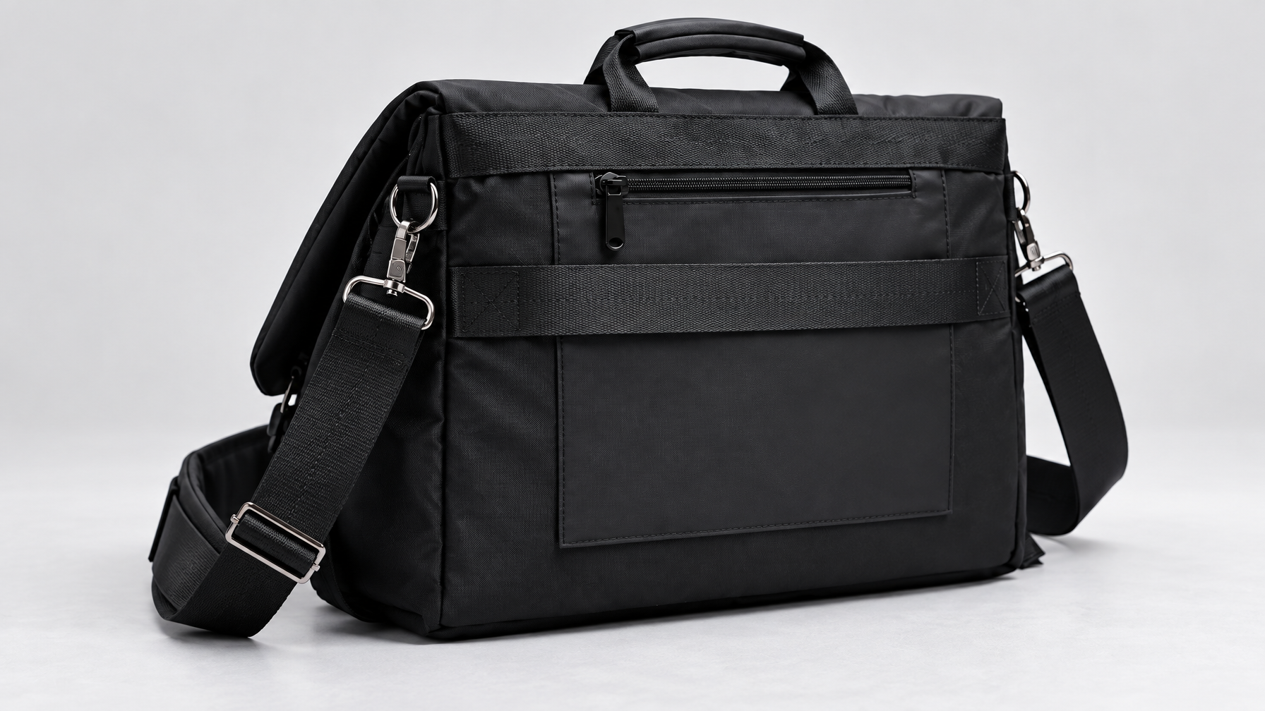 Back panel of a black Rook Brief showing the luggage pass-through sleeve on a light gray surface
