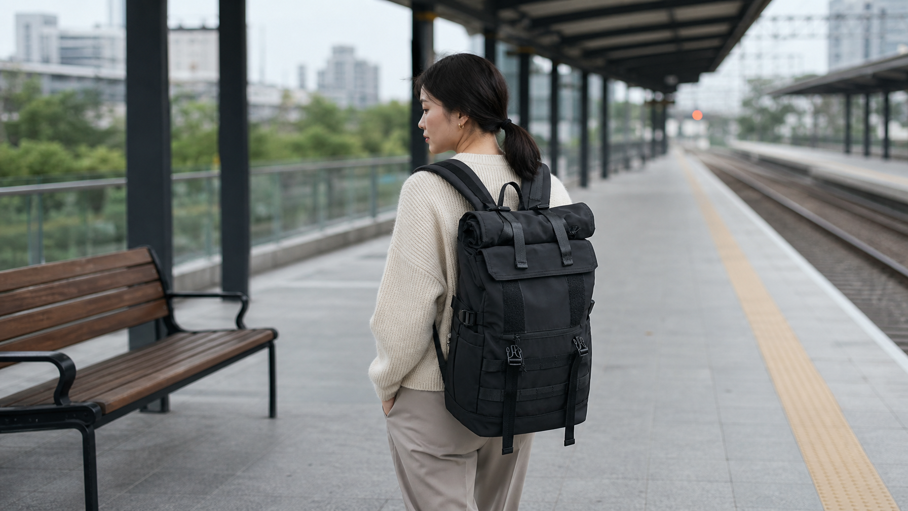 Traveler walking a regional train platform with a closed black expandable backpack on both shoulders