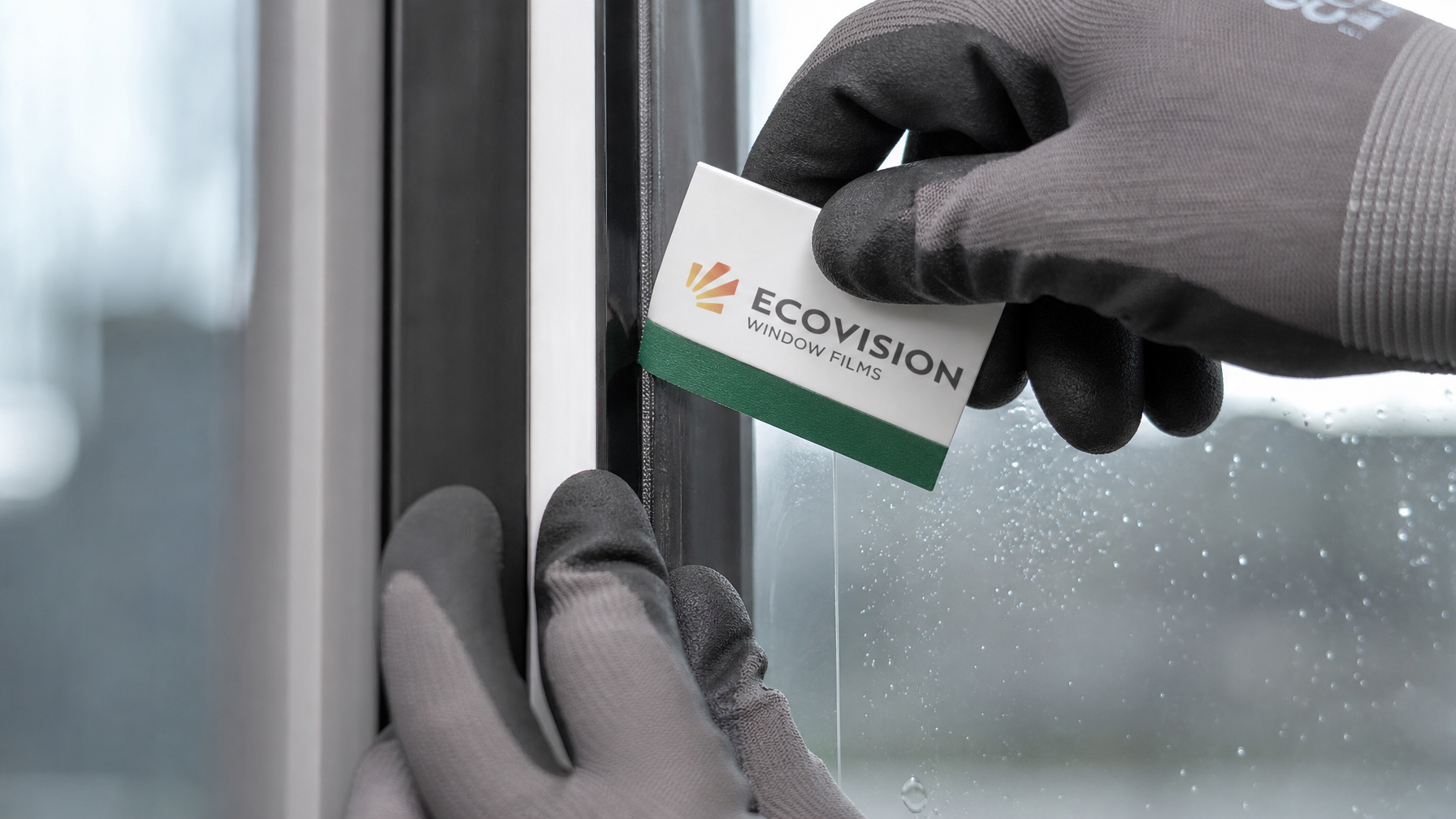 Close-up detail of professional installer applying security film edges to glass door frame with a hard card tool