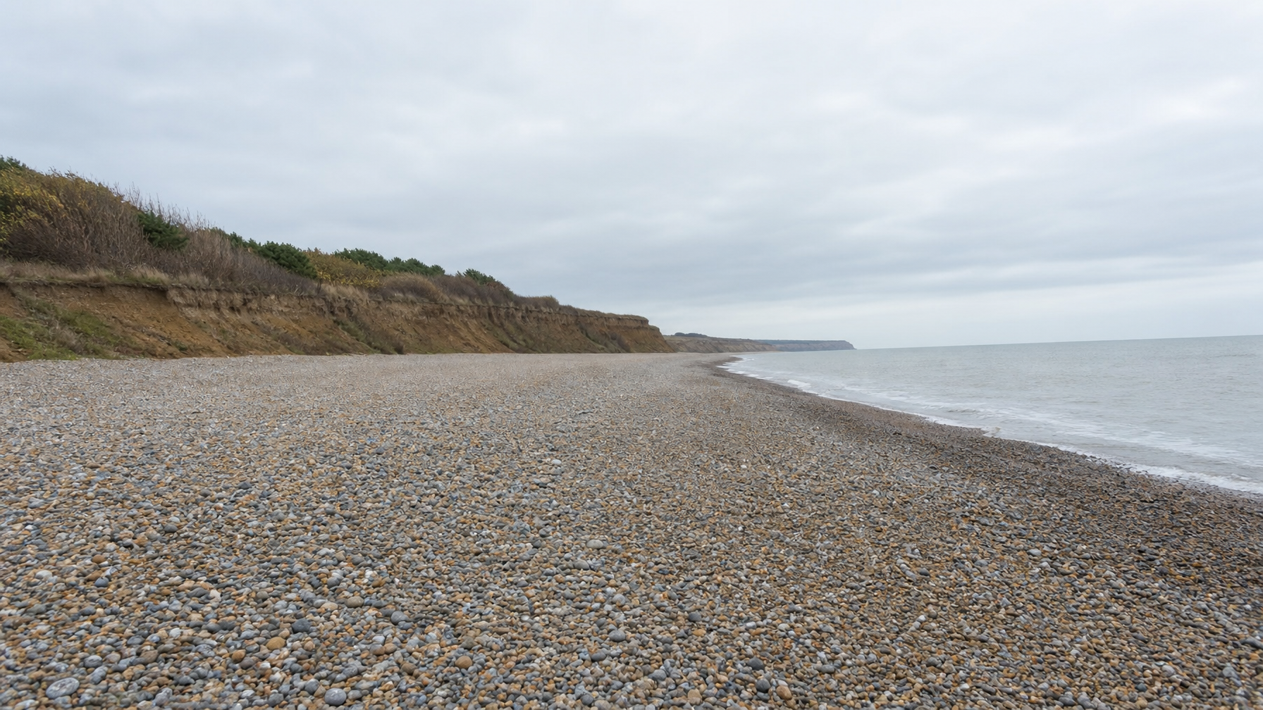 Flint pebble beach and North Sea at Weybourne, North Norfolk, UK, under grey coastal light