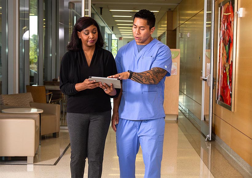 Woman and man in scrubs looking over a tablet.