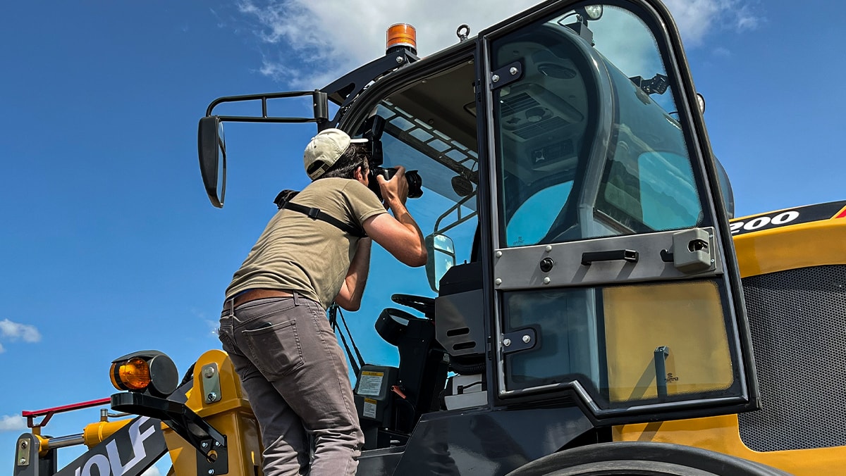 Man taking a picture of the interior cab of construction equipment.