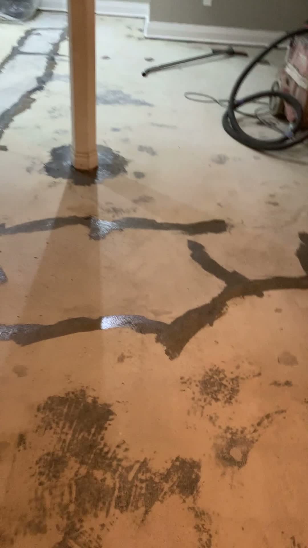 Wet concrete floor with dark stains around wooden pole