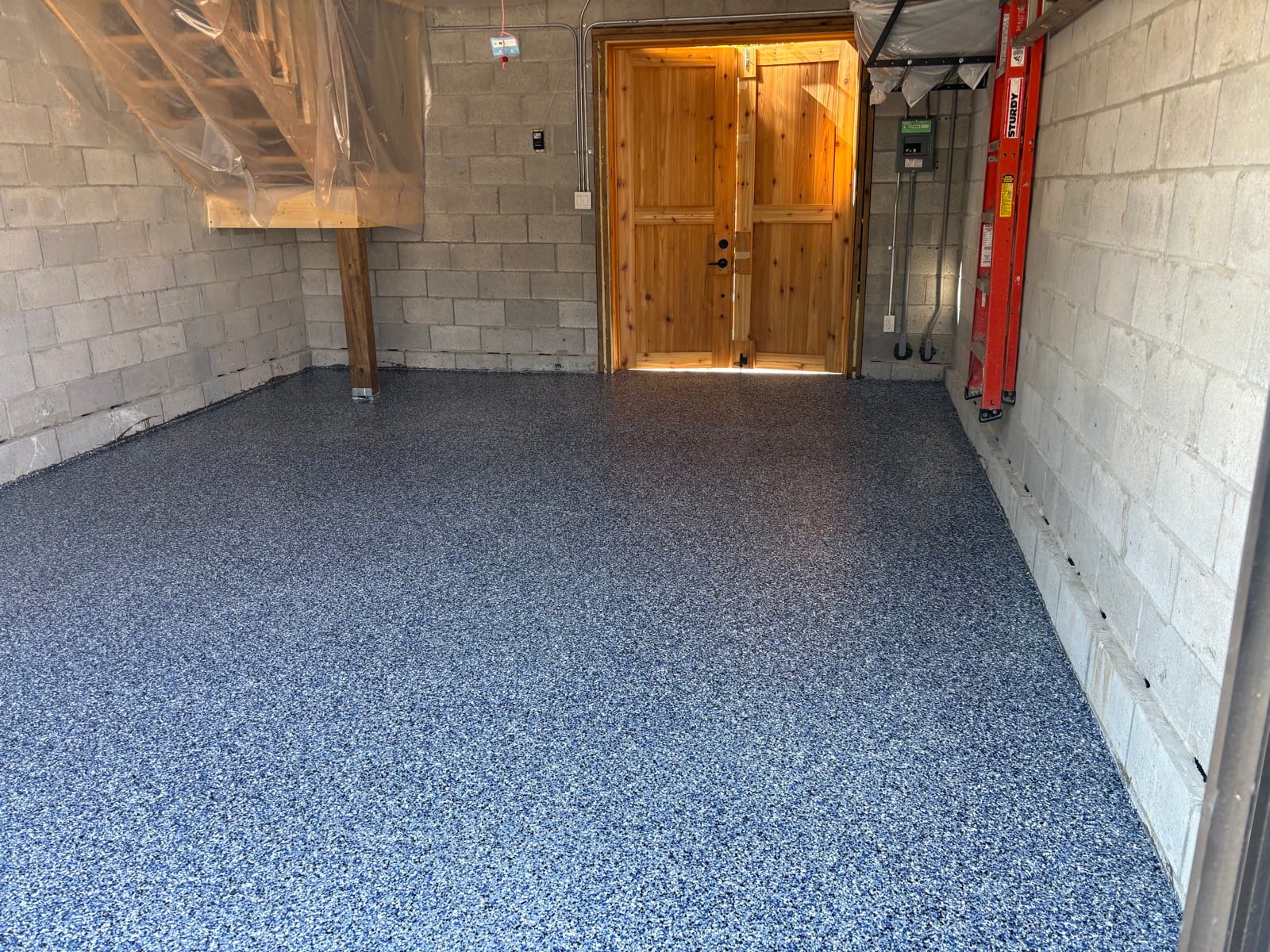 Blue epoxy garage floor with wooden doors and red ladder