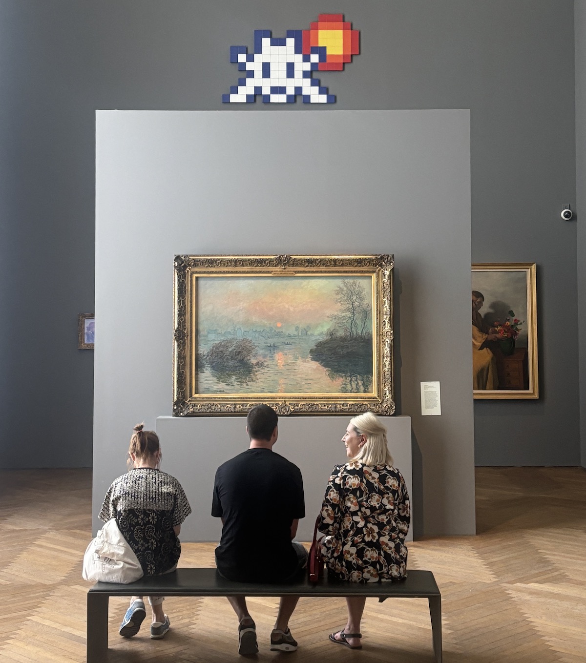 Une oeuvre d'Invader au-dessus du "Soleil couchant sur la Seine à Lavacourt, effet d'hiver" de Claude Monet dans le cadre de l'expositon "We are here" au Petit Palais / © Virginie Jannière pour Enlarge your Paris 