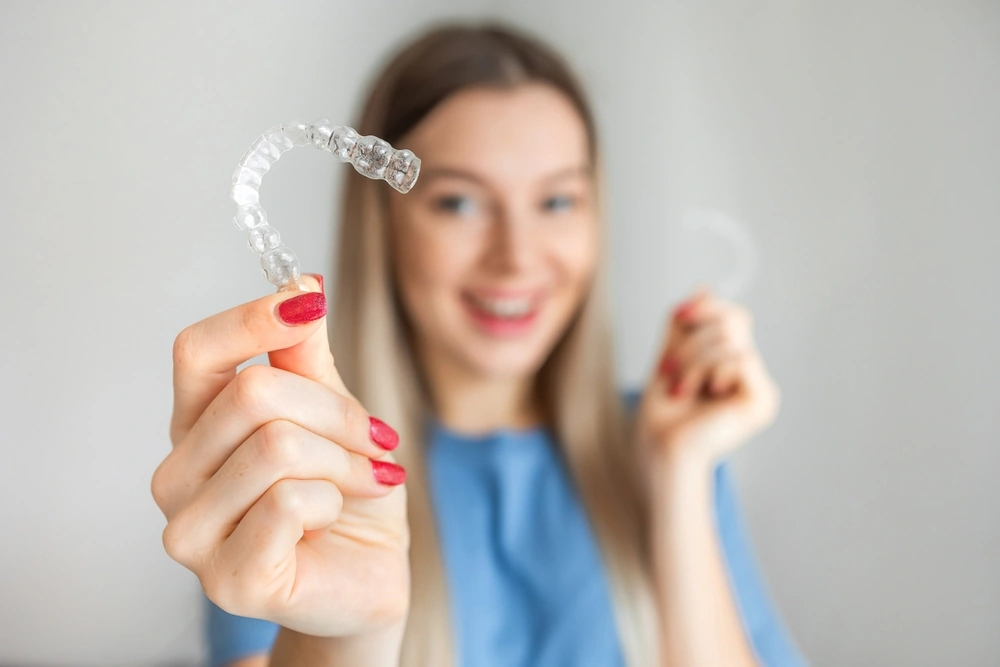 Patient holding a clear Invisalign aligner