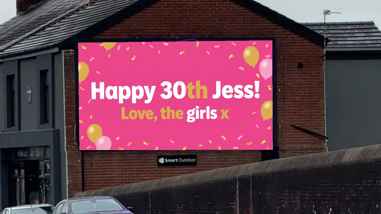 Example birthday billboard reading Happy 30th Jess! Love, the girls x, on a roadside digital screen on Blackpool Road, Preston
