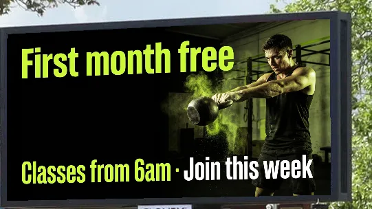 Example gym ad reading First month free, classes from 6am, on a roadside digital screen on Butts Road, Coventry