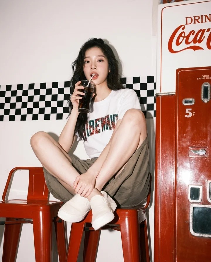 레트로 자판기 앞 붉은 스툴에 앉은 모델의 컷