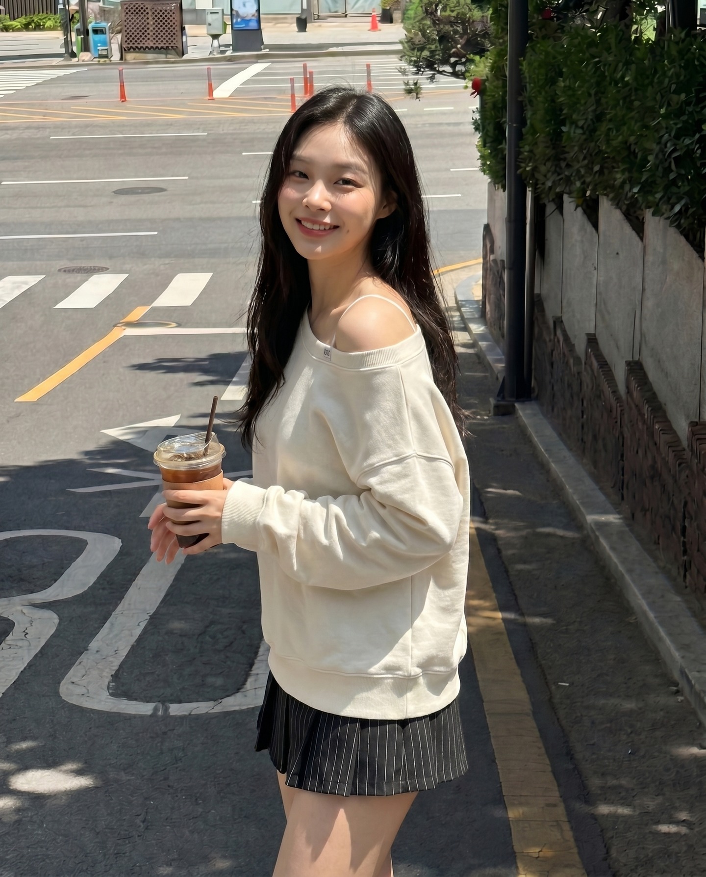 Model Korea berpakaian sweater off-shoulder krim memegang kopi ais di jalan raya Seoul