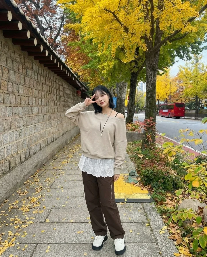 Model Korea berpakaian baju knit beige dan seluar wide-leg berjalan di lorong hanok berlatarkan daun luruh, Seoul