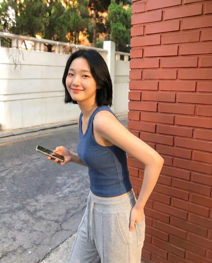 โมเดลเกาหลีทรงผมสั้นสวมเสื้อกล้ามสีน้ำเงิน ยืนในซอยกำแพงอิฐ