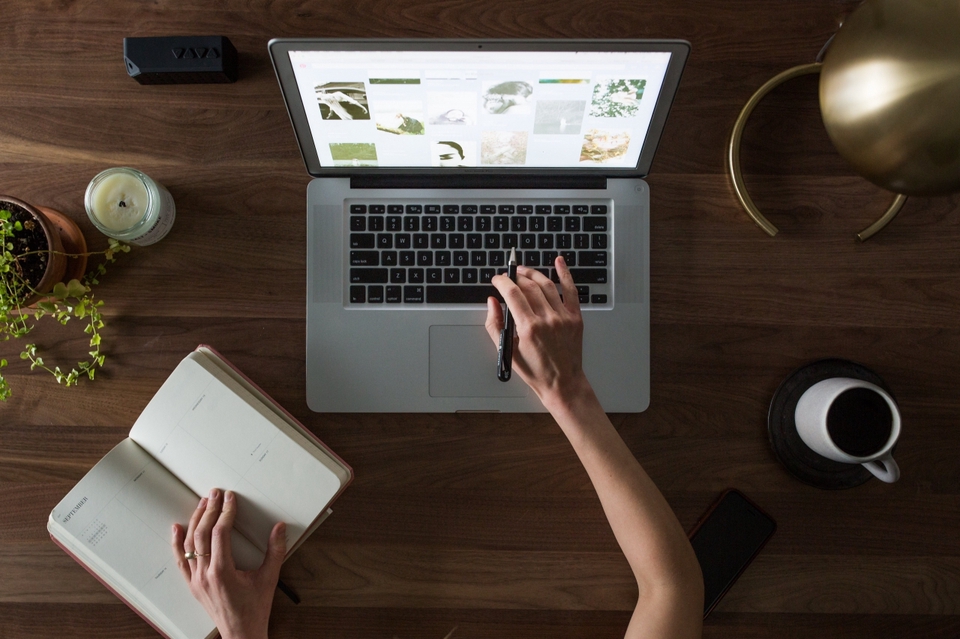 Viết caption freelance: Chuyên gia tự do làm việc tại nhà, sử dụng laptop và sổ tay lên ý tưởng nội dung.