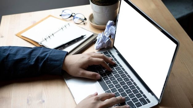 Freelancer viết content đang làm việc trên laptop, với bàn phím, màn hình hiển thị trống và tài liệu viết tay bên cạnh.