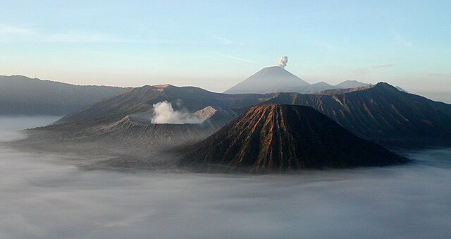 Gunung berapi di Indonesia dengan awan di atasnya. Bikin rencana liburan akhir tahun di Indonesia, hubungi jasa travel planner!