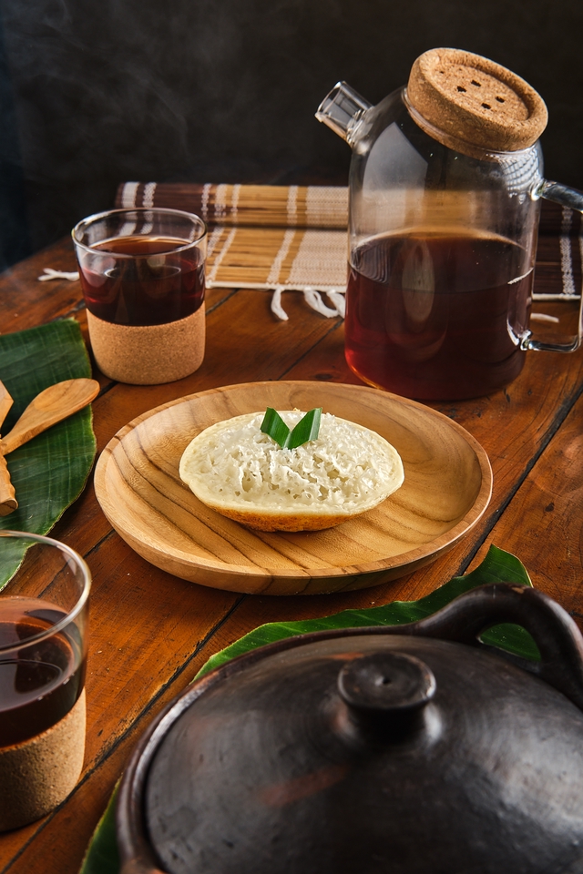 Jasa Fotografi Produk Makanan - Foto Serabi dengan Daun Pandan di atas Piring Kayu, Ditampilkan bersama Teh dan Peralatan Makan