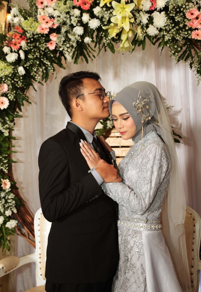 Jasa Fotografi Pernikahan - Pasangan pengantin tersenyum bahagia di depan dekorasi bunga