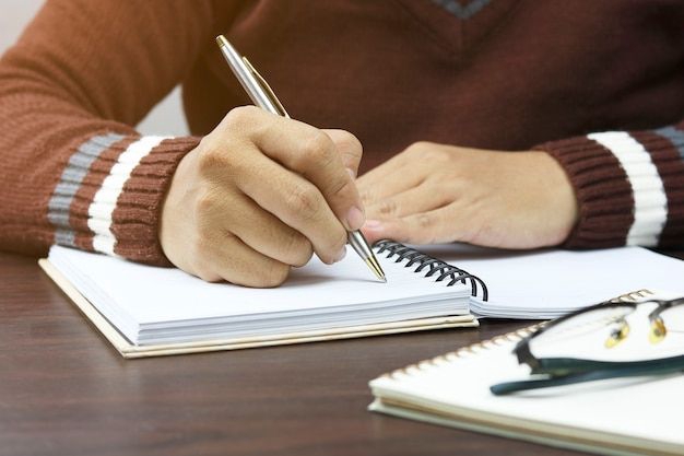 Jasa pengetikan online, seseorang sedang mengetik di buku catatan dengan pulpen.