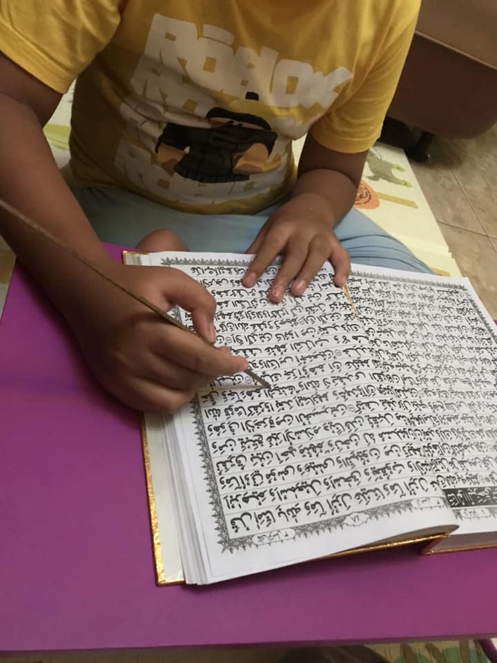 Anak sedang belajar membaca buku di meja dengan menggunakan pena, kursus online bahasa arab, belajar bahasa arab online, kelas bahasa arab online, kursus bahasa arab, belajar bahasa arab