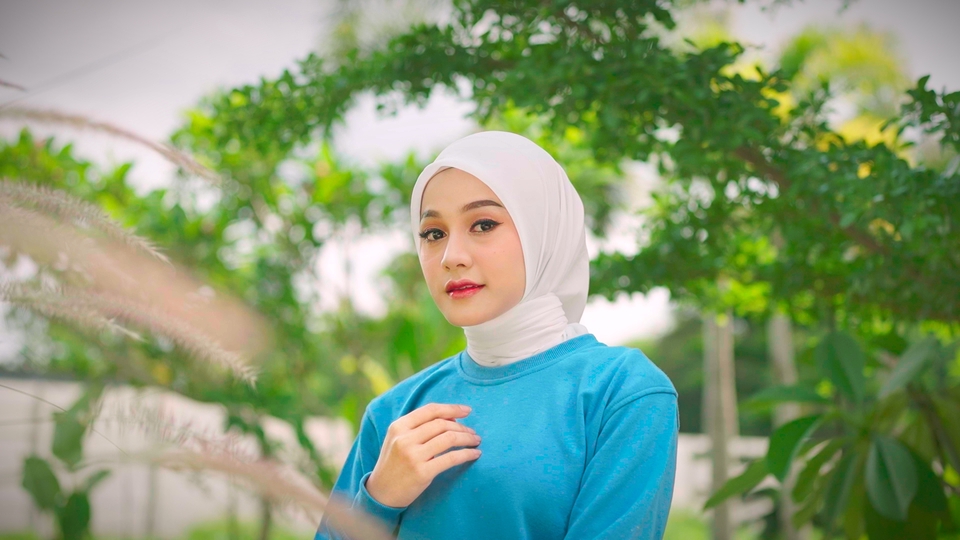 Jasa pembuatan video company profile dengan harga terjangkau, menampilkan seorang wanita mengenakan hijab putih di depan latar belakang taman hijau.