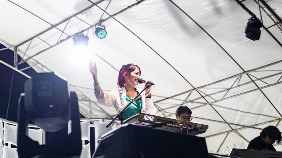 ช่างภาพหญิงกำลังร้องเพลงและเล่นคีย์บอร์ดบนเวที